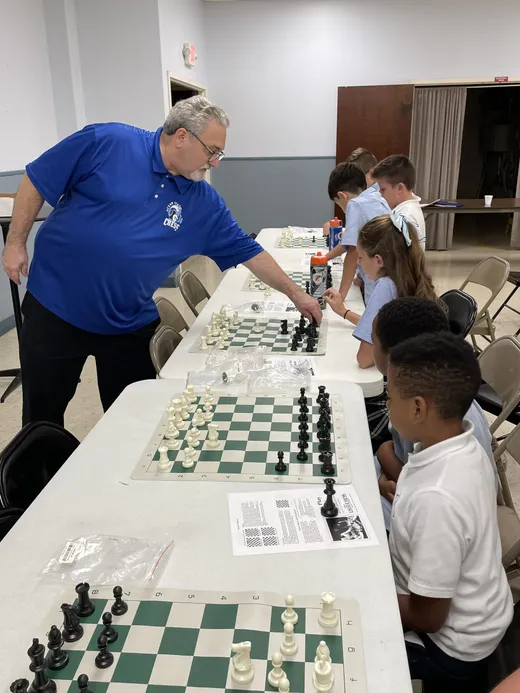 Students playing chess with their instructor at the SCA chess club