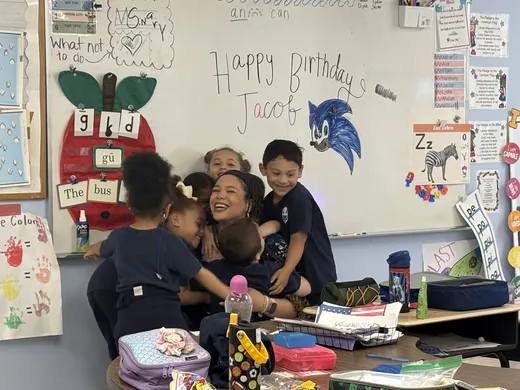 An SCA teacher surrounded by a group of students in the classroom